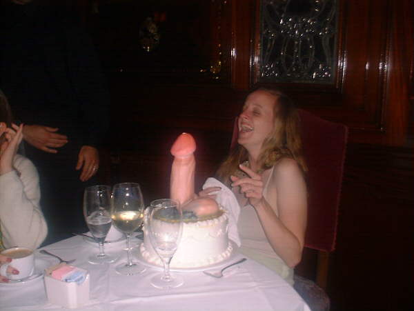 Outrageously phallic cake decoration; the female recipient appreciates the joke.