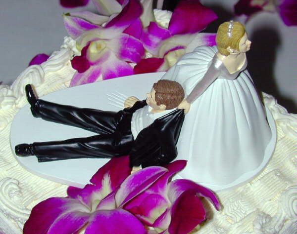 Decoration atop a wedding cake, showing the groom being dragged to the altar (or perhaps home afterwards to wash the dishes).